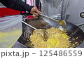chef actively stirring fried rice in a large wok, showcasing professional cooking techniques and steaming preparation in a kitchen environment. An example of authentic culinary skill and efficiency. 125486559