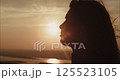 Young woman watching golden sunset over river 125523105