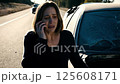 A woman on the phone after a car accident, her expression showing concern and distress as she speaks 125608171