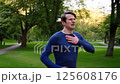 A male runner experiencing a sharp pain in his right side during a morning run in a park 125608176