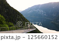 Young man is staying on the viewing platform with drone controller view of Alps mountains and lake 125660152