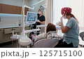 Young female dentist treats a woman patient in a bright, modern dental clinic. She works with 125715100