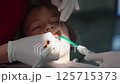 Close-up of a young boy receiving an ultrasonic dental cleaning at the dentist office. Two dental 125715373