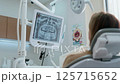 Young female dentist treats a woman patient in a bright, modern dental clinic. She works with 125715652