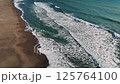 Powerful waves rolling, crashing against sandy coastline, highlighting dynamic marine energy and natural rhythmic movement 125764100