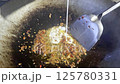 Asian cook is cooking in thai kitchen in local traditional country style, preparing sizzling thai green curry paste being stir fried in traditional wok to cook thai food green curry popular worldwide 125780331