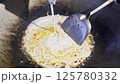 Asian cook is cooking in thai kitchen in local traditional country style, preparing sizzling thai green curry paste being stir fried in traditional wok to cook thai food green curry popular worldwide 125780332