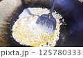 Asian cook is cooking in thai kitchen in local traditional country style, preparing sizzling thai green curry paste being stir fried in traditional wok to cook thai food green curry popular worldwide 125780333
