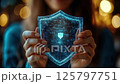 Digital blue holographic shield with glowing particles and protection symbol held in hands against dark background with bokeh lights, representing cybersecurity and data 125797751
