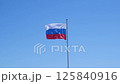 Large flag of the Russian Federation on a flagpole against a blue sky. Close up 125840916