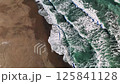 Aerial view revealing turquoise ocean waves rolling, white foam washing across sandy shoreline, generating dynamic coastal landscape pattern 125841128