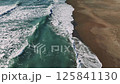 Turquoise ocean waves rolling, gently crashing onto sandy shoreline, revealing rhythmic marine energy and serene coastal landscape 125841130