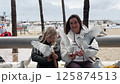 Mother and daughter feeding pigeons on a promenade 125874513