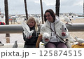 Mother and daughter feeding pigeons on a promenade 125874515