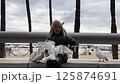 Blonde girl feeding pigeons on a promenade 125874691