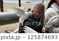 Mother and daughter feeding pigeons on a promenade 125874693