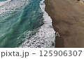 Aerial view capturing turquoise waves rhythmically washing sandy coastline, displaying stunning oceanic landscape and natural dynamic motion 125906307
