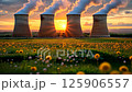 Cooling towers stand tall against a vibrant sunset with flowers in the foreground 125906557