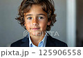 Young boy in formal attire smiling confidently at a professional setting 125906558
