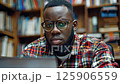 Focused student studying in a library with shelves of books in the background 125906559