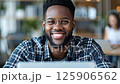 Young man smiling while working on laptop in a modern cafe setting during the day 125906562