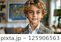 Young boy in stylish suit smiles in cozy living room with world map in background 125906563