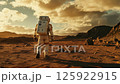 An astronaut is walking on the stunning Mars landscape while the sun sets beautifully on the horizon An astronaut is walking on the stunning Mars landscape while the sun sets beautifully on the horizon 125922915