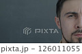 Slow motion portrait of anxious biracial man half face looking at camera on gray color background. People and negative emotion concept. 126011055