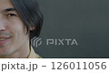 Slow motion portrait of happy Asian man half face looking at camera smiling on gray color background. Positive emotion and cheerful person concept. 126011056