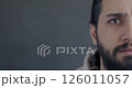 Close-up portrait of worried Middle Eastern man half face looking at camera on gray color background. Negative emotion and people concept. 126011057