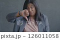 Slow motion portrait of unhappy young woman showing thumbs-down hand gesture on black color background. Negative emotion and people concept. 126011058