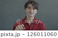 Slow motion portrait of happy young man waving hand smiling looking at camera on black color background. People and expression concept. 126011060
