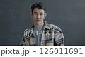 Portrait of joyful Asian man making online video call using earphones talking looking at camera on gray color background. People and communication concept. 126011691