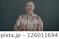 Slow motion portrait of friendly Asian lady waving hand smiling looking at camera on gray color background. People and expression concept. 126011694