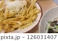 Overhead pan on served food dishes from crispy fries topped with cheese to a risotto, fried squid with onions and shrimps with a slice of lemon to the side. 126031407