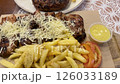 Overhead pan on juicy grilled chicken topped with cheese alongside crispy fries and fresh tomato slices and greek meatball burger with paprika sauce to the side. 126033189