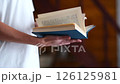 A woman in a white T-shirt flips through and reads a close-up blue book. High quality FullHD footage 126125981