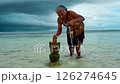 Indigenous man performs sacred ritual, placing wooden totem calm ocean shallows. Ancient ritual connects spirit world nature, cultural traditions preserved. Solemn ritual offers ancestral beliefs. 126274645