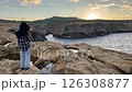 A boy on a rock near the sea. A beautiful sea sunset. 126308877