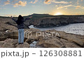 A boy on a rock near the sea. A beautiful sea sunset. 126308881