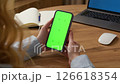 Woman use digital tech cell phone open green screen mock up. Hand press click phone web site down middle center. Girl hold mobile. Turn on chroma key page. Cozy home background. Online app copy space 126618354
