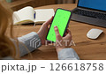 Woman sit use digital tech cell phone, green screen mock up. Hand scroll phone web site, swipe like photos. Girl hold mobile closeup. Chroma key page. Cozy office background. Online app copy space. 126618758