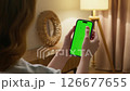 Woman use digital tech cell phone with green screen mock up. Hand tap press phone web site, open app. Girl hold mobile closeup. Turn on page. Cozy home background. Click online game copy space. 126677655