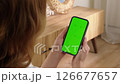 Woman use digital tech cell phone green screen mock up talk video call. Hand press click phone web site middle center. Girl hold mobile. Chroma key page. Cozy home background. Online app copy space. 126677657