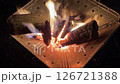 夜の屋外で火がついた木に強い風を送る 126721388