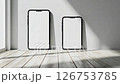 Modern mobile smartphone with white screen, label-free, hovers above white floor against a white background with soft shadow. The phone is slightly angled from the front view on the left.	 126753785