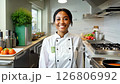A 27-year-old black female chef walks confidently through a vibrant kitchen, as the camera slowly zooms in with soft lighting 126806992
