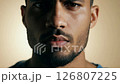 Close-up video of a determined middle-eastern man with a trimmed beard, static camera, soft diffused light, neutral beige background 126807225