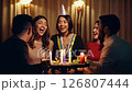 a static video with practical lighting of friends singing to a birthday celebrant in a dimly lit bar 126807444