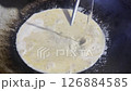 Asian cook is cooking in thai kitchen in local traditional country style, preparing sizzling thai green curry paste being stir fried in traditional wok to cook thai food green curry popular worldwide 126884585
